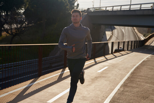 Man running on a road in sunlight