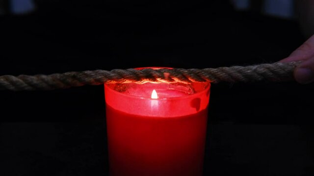 Burning a jute rope on the fire of a candle for the shibari ritual. 