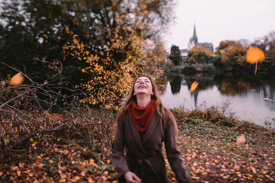 Happy woman playing with autum leaves