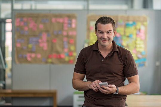 Portrait of smiling businessman with cell phone in office