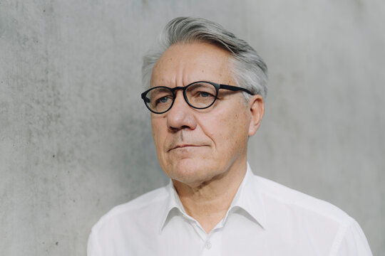 Portrait of a pensive senior businessman at a concrete wall