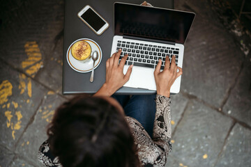 Top view of young woman using laptop at a pavement cafe