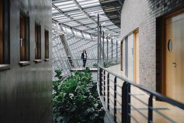 Businesswoman standing on a skywalk in modern office building