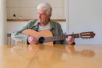Thoughtful retired man practicing guitar while looking away at home
