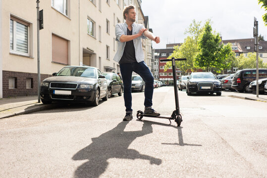 Man standing on street with E-Scooter