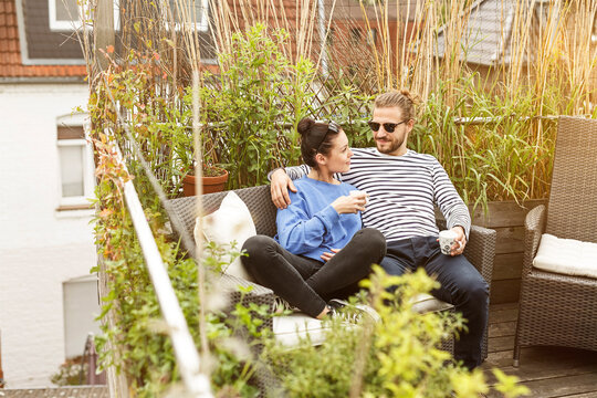Young couple relaxing on their balcony, sitting on couch