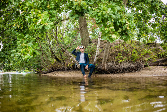 Businessman at lakeshore with VR glasses looking out