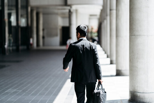 Rear view of young businessman walking in the city - Powered by Adobe