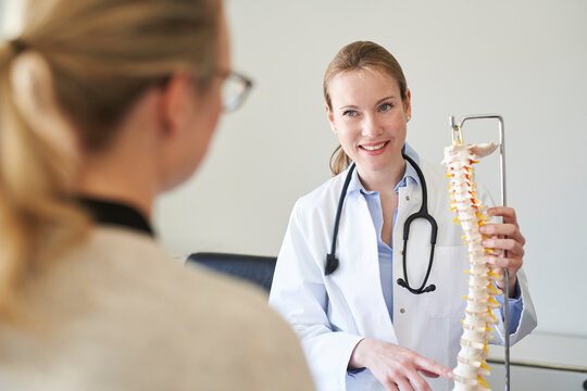 Female doctor explaining spine model to patient in medical practice