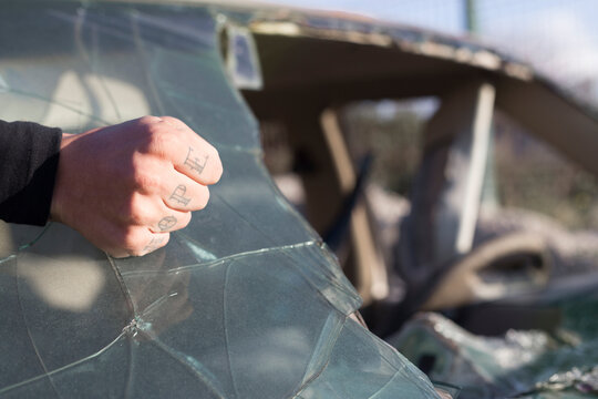 Fist of a young man with HOPE tattoo on broken windscreen on a scrapyard
