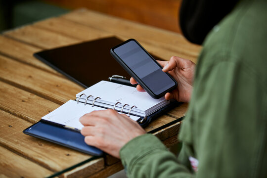 Man with diary using mobile phone at table