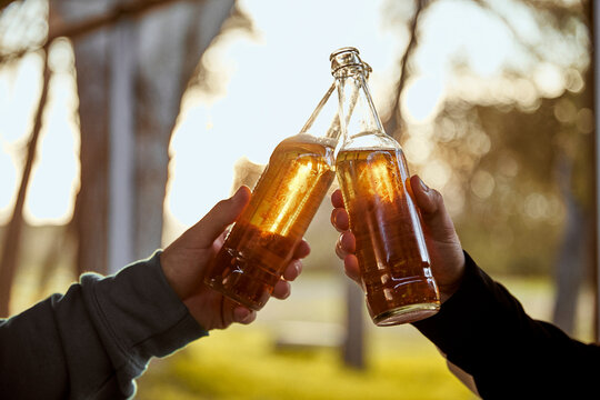 Hands of two male friends toasting with beer bottles