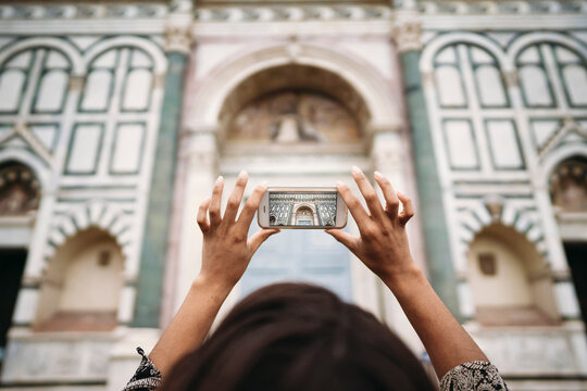 Close-up of young woman taking a smartphone picture in the city, Florence, Italy