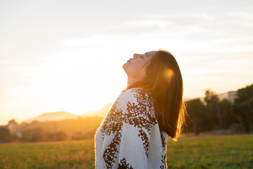 Young woman relaxing with head back during sunset