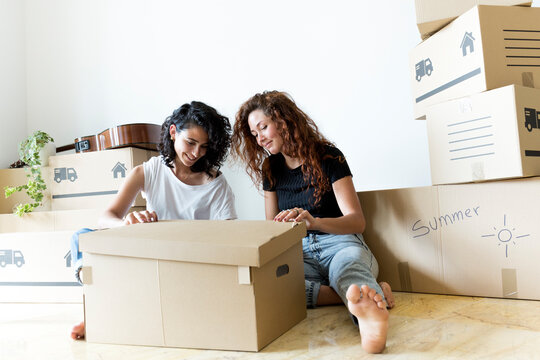 Two Friends Moving Into New Home Opening Cardboard Box