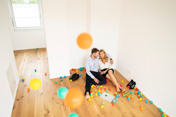 Business couple sitting on floor of their new home with colorful balls