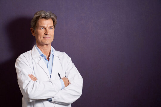 Portrait of confident doctor in front of a purple wall