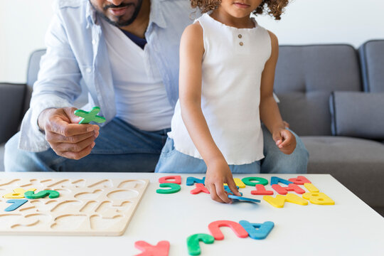 Father and daughter playing with alphabet learning game at home