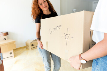 Two friends moving into new home carrying cardboard box together