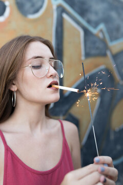 young woman lighting cigarette with a sparkler