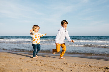 Boy and his little sister playing on the beach