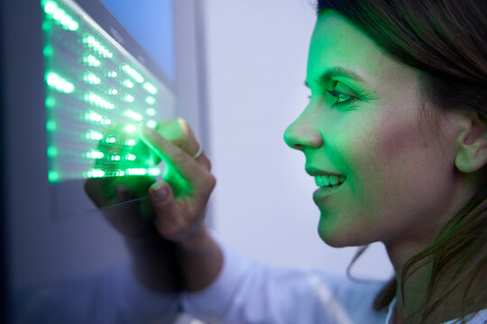 Close-up of smiling woman touching green led touchscreen