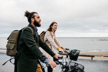 Couple riding e-bikes on beach promenade
