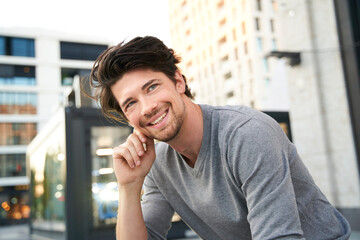 Portrait of smiling man wearing grey shirt in the city