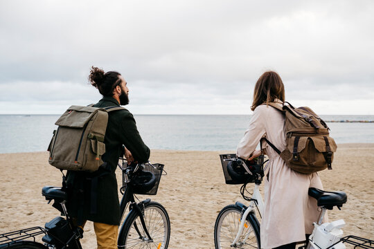 Couple with e-bikes on the beach looking at the sea