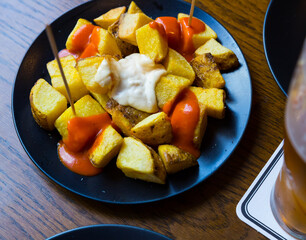 Top view of Patatas bravas, traditional Spanish dish of fried potatoes served with cheese sauce and spicy sauce with paprika. High quality photo