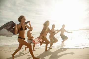 Group of friends running at beach on sunny day