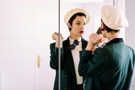 Fashionable young woman checking her look in the mirror