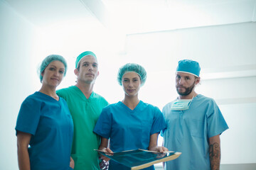 Confident team of surgeons standing with medical x-ray image in hospital