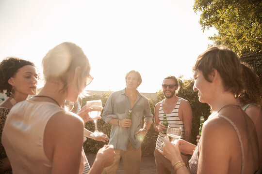 Happy friends enjoying summer while drinking alcohol against sky