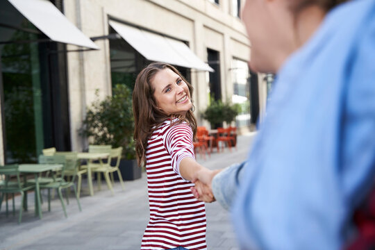Happy woman hand in hand with man in the city