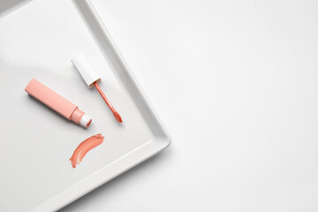 Plate with lipstick on white background