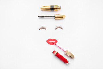 Creative composition with false eyelashes, paper-cut lips and cosmetics on white background