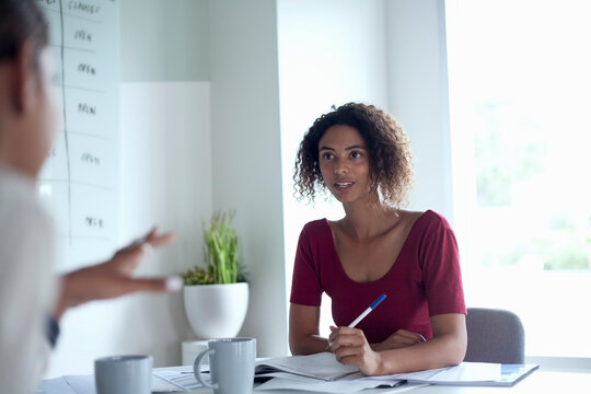 Female colleague looking at businesswoman during meeting in office
