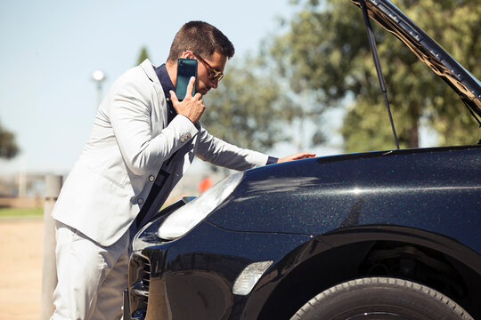 Young businessman having a car breakdown, talking on the phone