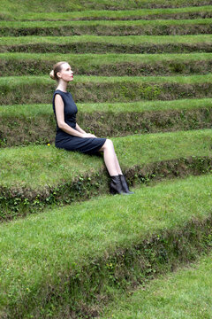 Italy, Alto Adige, Lana, woman sitting on grass-covered steps of natural open air theater
