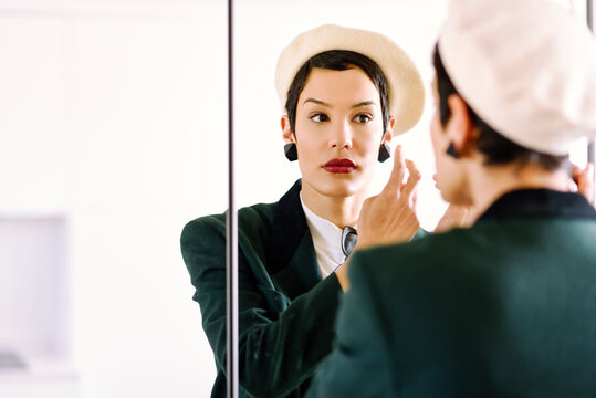 Fashionable young woman checking her look in the mirror