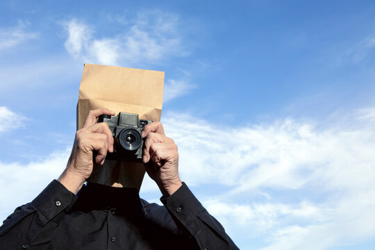 Man with paper bag above his head taking a picture