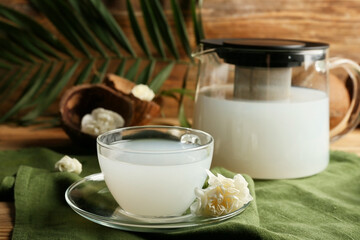 Cup of coconut milk with flower on table