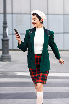 Fashionable young woman with cell phone crossing zebra crosssing