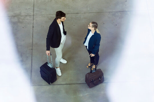 Two young business partners with baggage talking