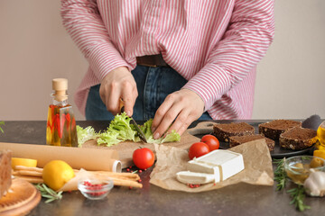 Woman cutting lettuce salad on table in kitchen