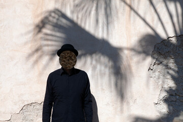 Morocco, Essaouira, man with obscured face wearing a bowler hat at a wall