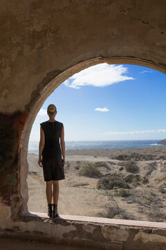 Spain, Tenerife, Abades, Sanatorio de Abona, woman standing at arched window in ghost town building