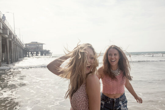 Young female friends enjoying weekend at beach against clear sky