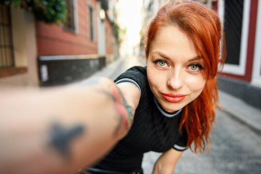 Selfie portrait of red-haired woman in the city